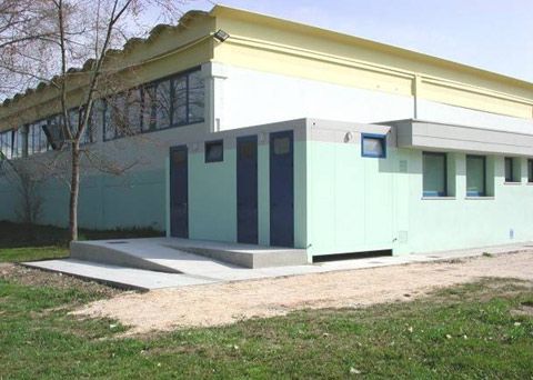 Particolare di integrazione di struttura prefabbricata ad uso servizi igienici in edificio sportivo esistente. Ripresi tinteggiatura esterna e colore dei serramenti