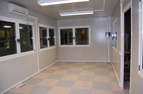 Particolare interno di ufficio prefabbricato con impianto elettrico a canalina a battiscopa e pavimento in quadrotti pvc bicolore